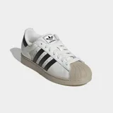 Championes Adidas Superstar II de diseño clásico con paneles divididos de cuero blanco y gamuza gris, con las icónicas tres tiras negras en el lateral, puntera de goma y suela en tono tostado.