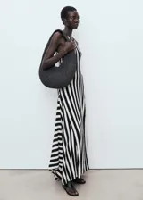 Vestido largo de punto fino con diseño evasé, cuello caja y tirantes anchos. Presenta un estampado de rayas verticales en blanco y negro y un bajo asimétrico.