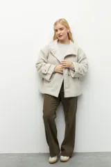 Tapado corto color beige de tejido grueso con cuello alto, cierre frontal con botones grandes veteados y bolsillos delanteros.