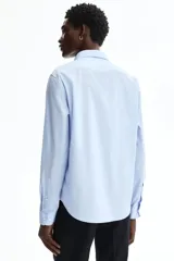 Camisa celeste de corte slim fit, con cuello inglés y cierre frontal de botones.