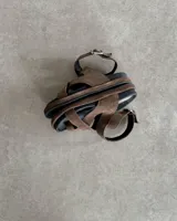 Sandalia marrón de cuero vacuno con tiras cruzadas y ajuste con hebilla al tobillo.