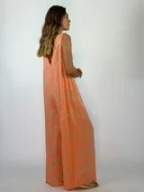 Mono largo de corte holgado con escote en V y sin mangas. Presenta un diseño estampado con líneas diagonales en tonos naranja y beige.