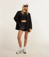 Short de jean negro de tiro alto y corte slim, con efecto desgastado, roturas sutiles y terminación deshilachada en las perneras. Cuenta con bolsillos clásicos y cierre frontal con botón y cremallera.