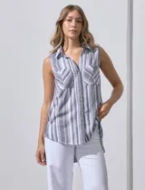 Camisa sin mangas de corte recto, con cuello clásico y escote en V. Presenta un diseño de rayas verticales en tonos lila, rosa, blanco y gris, con dos bolsillos frontales aplicados con estampado en chevron. Cuenta con cierre central de botones.