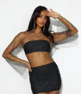 Vestido corto de red con brillos, mangas largas y cuello redondo. Incluye top y short negro.