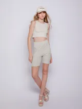 Calza ciclista color beige de tela brillante con textura acanalada y elástico en la cintura.