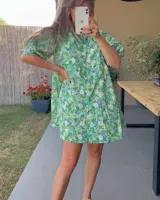 Vestido corto verde con estampado floral, cuello alto, mangas cortas abullonadas y corte holgado.