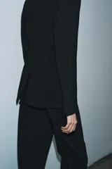 Blazer entallada de Zara Woman Collection, color negro, con cuello solapa de muescas, manga larga con botones en puños y cierre frontal con botones. Presenta bolsillos de vivo en el delantero y detalle de pespuntes marcados a tono.