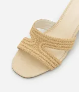Sandalia mule color beige con puntera redonda, tira ancha en forma de H con efecto ráfia y tacón bloque mediano.