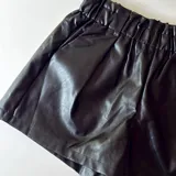 Short negro de cuero sintético con cintura elastizada y bolsillos laterales.