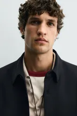 Sobrecamisa negra de corte regular, confeccionada en tejido compacto. Presenta cuello solapa, manga larga con puños abotonados y bolsillos de vivo en la cadera. Cierre frontal con botonadura.