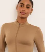 Campera deportiva de corte ajustado, confeccionada en tejido seamless de poliamida y elastano. Presenta cuello alto, cierre frontal con cremallera y textura acanalada.