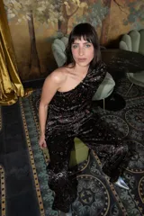 Mono largo de terciopelo negro con estampado paisley en tonos borgoña, verde y blanco. Diseño de un solo hombro con manga larga abullonada y pantalón palazzo.