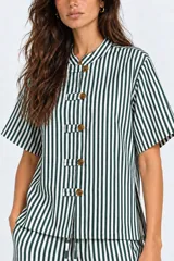 Blusa de algodón a rayas verde oscuro y blanco, con mangas cortas, cuello mao y detalle de botones tipo alamar en el frente. Presenta aberturas laterales en el ruedo.