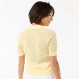 Remera de punto calado color amarillo, con cuello polo, manga corta y cierre frontal parcial con botones.
