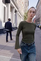 Camiseta de cuello redondo y manga larga con terminación acampanada en los puños, de corte ajustado al cuerpo.