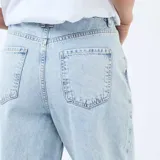 Jean de corte regular y cintura estándar, en color azul claro lavado. Presenta un diseño de pierna ancha con un detalle distintivo de dobladillo ancho en la parte inferior.