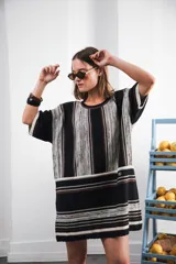 Vestido corto tejido a rayas horizontales en tonos beige y blanco, con cuello redondo y mangas cortas.