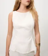 Blusa peplum sin mangas en sarga de algodón blanca, con escote redondo y diseño estructurado con volado amplio en el ruedo.