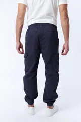 Pantalón cargo estilo jogger color azul marino con cintura elástica ajustable con cordón, bolsillos laterales y bolsillos cargo con solapa en los muslos. Tobillos elastizados.