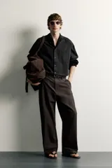 Pantalón barrel fit de corte ancho color marrón, confeccionado en mezcla de algodón y lino. Presenta bolsillos frontales, bolsillos traseros de vivo y cierre frontal con cremallera y botón.