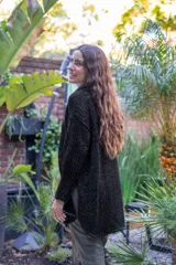 Camisa de punto calado en color beige con hilo de lurex. Presenta una silueta oversize, cuello camisero clásico, mangas 3/4 ligeramente abullonadas y cierre frontal con botones metálicos.