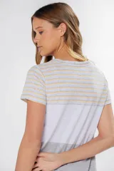 Remera de manga corta con cuello redondo y bolsillo frontal. Presenta un diseño de bloques de color y rayas horizontales: la parte superior (hombros y mangas) tiene rayas finas amarillas, grises y celestes; la parte media es blanca jaspeada con un bolsillo; y la parte inferior es gris jaspeada.