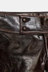 Shorts de tiro bajo confeccionados en material con acabado efecto cuero brillante. Presentan cintura ancha con detalle de botones forrados en el frente y cierre frontal con cremallera.