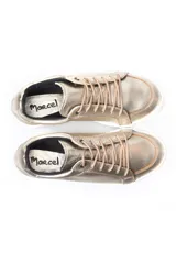 Zapatillas deportivas de cuero, combinando paneles en color blanco y detalles metalizados en tono dorado. Presentan cierre mediante cordones blancos y suela de goma plana.