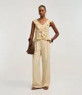 Pantalón de vestir de mujer, tiro alto, corte wide leg, color beige claro. Presenta pliegues frontales y frisos marcados.