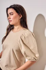 Remera de algodón negro con mangas cortas abullonadas, cuello redondo y costura central frontal.