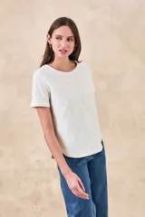 Remera de algodón color blanco con bordados florales y geométricos en color negro. Presenta cuello redondo, mangas cortas y un diseño con franjas horizontales bordadas.