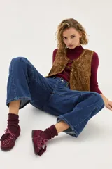 Mocasín de gamuza color bordó con detalle de flecos, cordones y tachas metálicas en la parte superior.