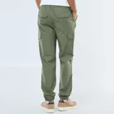 Pantalón cargo de hombre color verde militar, con múltiples bolsillos laterales y puños ajustados elásticos en los tobillos. Presenta cintura elástica con cordón de ajuste.
