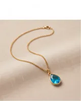 Collar de bronce con cadena fina de eslabones y un dije colgante en forma de lágrima con piedra azul translúcida en bisel dorado.