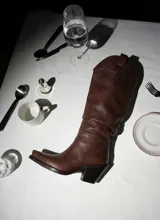 Bota de caña alta estilo western confeccionada en cuero vacuno con acabado texturizado. Presenta un diseño de punta cuadrada, taco bloque de altura media y tiradores laterales en la parte superior de la caña.