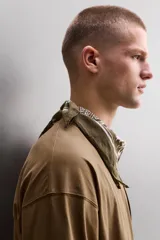 Camiseta de algodón de corte relajado (relaxed fit), color verde oliva, con cuello redondo, manga larga y bolsillo plastrón con cierre de cremallera en el pecho.