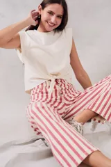 Pantalón de jean de corte recto, tiro medio, con estampado a rayas verticales rojas y crudas y cierre frontal con botones.