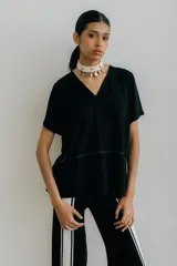 Remera negra de corte holgado con cuello en V y mangas cortas. Presenta costura horizontal a la altura del pecho.