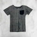 Remera gris con efecto marmolado y bolsillo negro en el pecho.