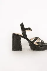 Sandalias de tacón alto y plataforma, color negro, con capellada de tiras cruzadas y cierre de hebilla en el tobillo. Cuentan con textura grabada en todo su diseño.