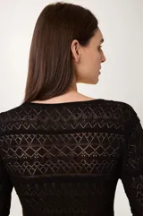 Vestido largo de punto calado color negro, con mangas largas y escote en pico con cierre de lazada.