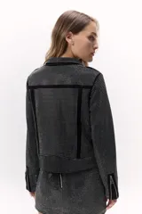 Campera negra de corte rockero con tachas plateadas, cierre asimétrico y cuello solapa.
