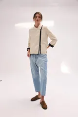 Chaqueta de lino lavado color blanco, con cuello mao, cierre metálico diagonal y detalles en contratono.