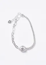 Pulsera semi-tennis de plata 925 combinada con cadena de eslabones y una zirconia ovalada central rodeada de piedras más pequeñas. Cuenta con cadena de alargue y dije en forma de corazón con grabado 925.