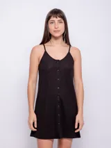 Vestido corto negro, sin mangas, con escote redondo y cierre frontal de botones.