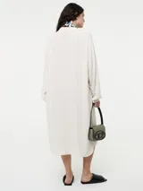 Vestido camisero negro de lino con botones delanteros y bolsillos ocultos.