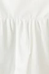 Vestido midi de algodón color blanco, con escote corazón, breteles anchos y espalda con punto smock. Presenta cuerpo entallado, costura fruncida en la cintura y pollera con vuelo, con ribetes negros en contraste en el escote y el bajo.