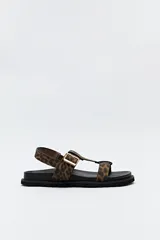 Sandalia plana con estampado animal, base de goma dentada y hebilla metálica ajustable.