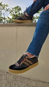 Zapatillas de cuero negro con detalles de estampado animal print de leopardo en las bandas laterales y en la puntera. Cuenta con suela de goma color tostado y cordones negros.